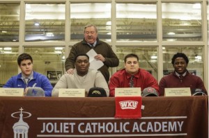 (Lathan Goumas – lgoumas@shawmedia.com) Head coach Dan Sharp talks about Bradley Krisch (from left), Kenneth Aguirre, Tyler Witt and Ze'veyon Furcron as they prepare to commit to NCAA Division One schools Wednesday during a National Letter of Intent Signing Day event at Joliet Catholic Academy in Joliet. Twelve total students signed letters of intent to compete in collegiate athletics.